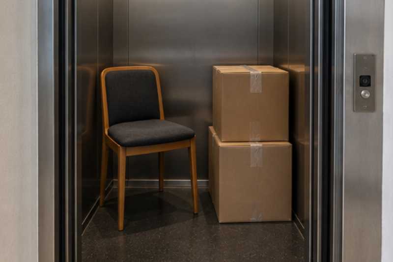 Chaise et cartons dans un ascenseur étroit, trop étroit pour ce qui était long
