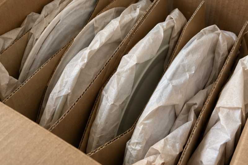 Assiettes emballées dans du papier dans un carton à séparateurs, une vaisselle sans aucun jeu