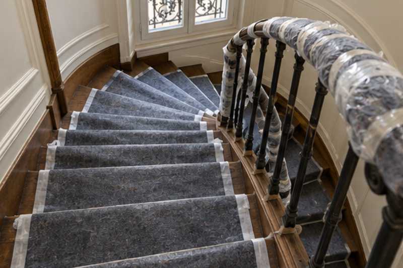 Marches d'un escalier ancien couvertes de couvertures antidérapantes et rampe protégée, escalier ancien protégé