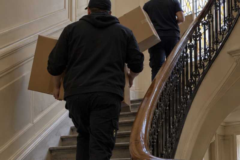 Déménageurs se passant des cartons dans un escalier, trois déménageurs pour un T2 bien rempli